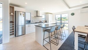 A modern kitchen with a central island, stainless steel appliances, and a view of the outdoors.