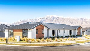 A modern residential building with a flat roof, large windows, and a well-maintained lawn.