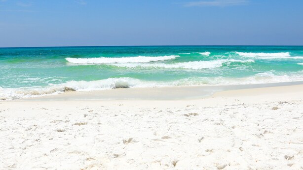 A beach with white sand and turquoise ocean waves. - Sleeps 6- 2 bedrooms with private baths, crib, bay access, pool, mins to Beach! (Navarre)