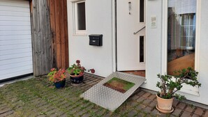 Ein Haus mit Garage, Holztür, Briefkasten, Blumentopf und Fußmatte.