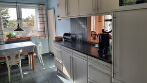 Eine Küche mit Esstisch, Stühlen, einer Mikrowelle und einem Kühlschrank.