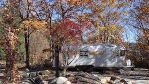 A white RV parked in a rocky area with autumn foliage. - AGS Trailer House - Campground (Hakuba)