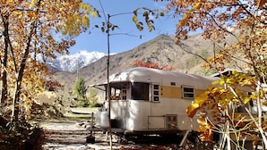 A vintage camper parked in a natural setting with mountains in the background. - AGS Trailer House - Campground (Hakuba)