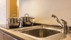 A stainless steel kitchen with a sink, two pots, and a faucet.