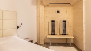 A modern room with a bed, a bench, and a wall-mounted light fixture.
