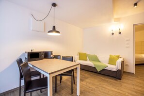 Une pièce moderne comprenant une table à manger, des chaises, un canapé et un four à micro-ondes.