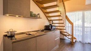 Una cocina moderna con estufa integrada, cafetera y escalera de madera.