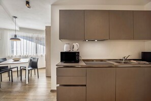 A modern kitchen with a built-in microwave, a kettle, and a stainless steel sink.