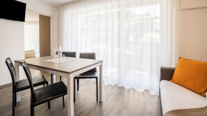 A modern room with a dining table, chairs, a sofa, and a TV mounted on the wall. - Apartment Treï Residence Bun Sté with Mountain View, Sauna, Wi-Fi, Terrace & Balcony (San Vigilio di Marebbe)