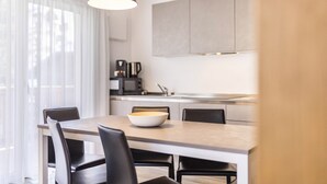 A modern kitchen with a dining area, featuring a large island, black chairs, and a hanging light fixture. - Apartment "Sis Residenz Bun Sté" with Mountain View and Sauna (San Vigilio di Marebbe)