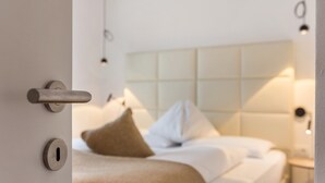 Una habitación de hotel con cama, cabecera, mesita de noche y una puerta con cerradura.