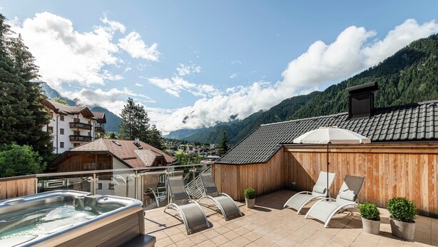 Una terraza en la azotea con un jacuzzi, sillones de descanso y plantas en macetas.