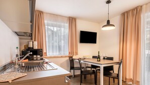Una cocina moderna con comedor, electrodomésticos de acero inoxidable y un televisor de pantalla plana.