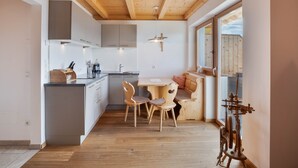 Moderni keittiö, jossa on puupalkkeja, ruokailutila tuoleineen ja suuri ikkuna.