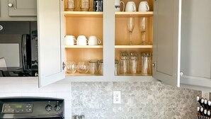 Cucina con pensili aperti che espongono diversi bicchieri e stoviglie.
