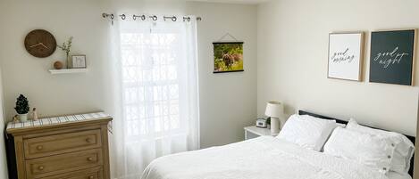 A bedroom with a bed, dresser, bedside table, and wall decorations.