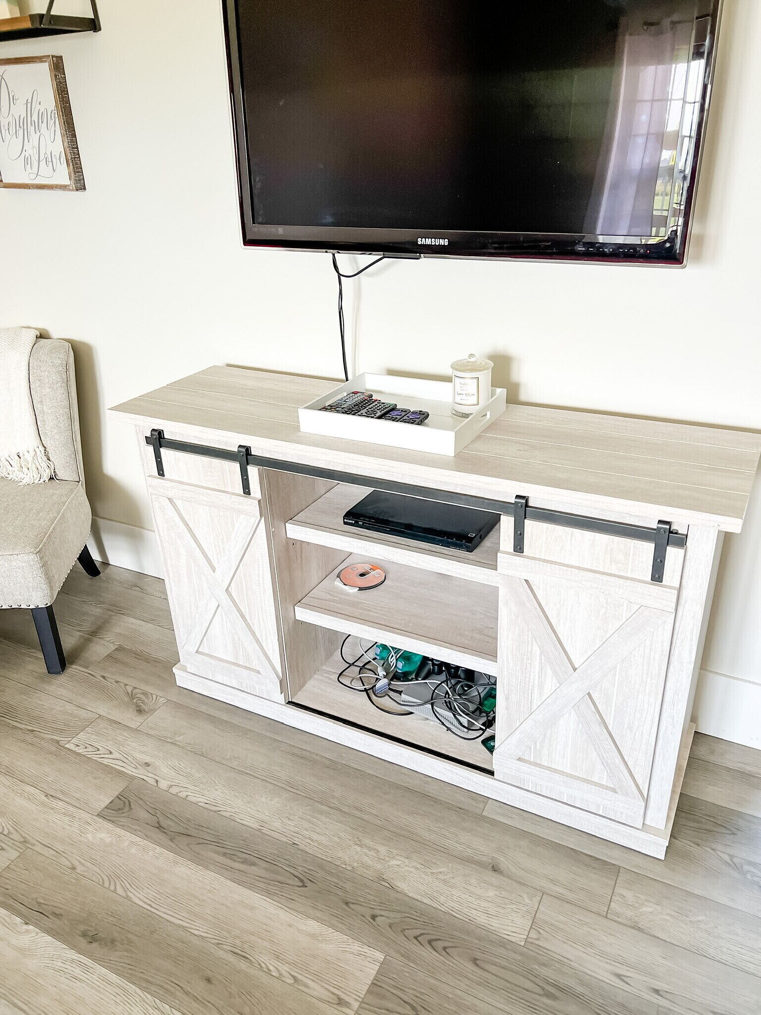 Una habitación con un televisor montado en la pared, un armario blanco con puerta corredera y una silla.