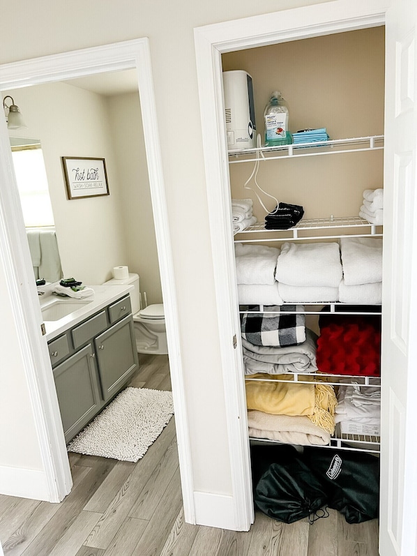 Une salle de bain bien rangée, avec un porte-serviettes, un panneau décoratif encadré et des toilettes.