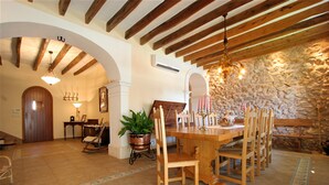 Un comedor con una mesa y sillas de madera, un candelabro y una pared de piedra.