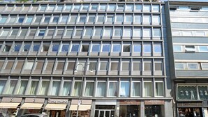 Ein mehrstöckiges Gebäude mit moderner Fassade, großen Fenstern und Geschäften im Erdgeschoss.