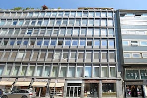 Un immeuble à plusieurs étages doté d’une façade moderne, de grandes fenêtres et de vitrines au niveau du rez-de-chaussée.