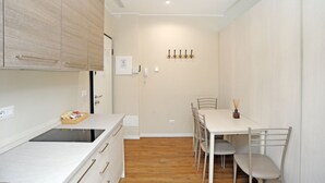 Eine moderne Küche mit Essbereich, Holzboden und einer weißen Wand mit Kleiderhaken.
