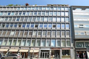 A multi-story building with a modern facade, large windows, and storefronts on the ground level.