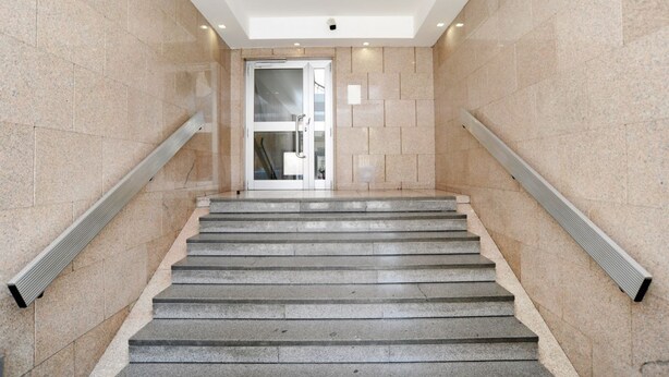 Eine moderne Treppe mit einer Glastür oben, die zu einem Innenraum führt.