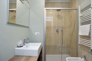 Une salle de bain moderne avec une douche à parois de verre, un lavabo blanc et un miroir.