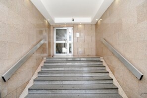 A modern staircase with a glass door at the top, leading to an interior space.