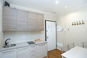 A compact kitchen with a sink, cabinets, and a door with a notice.