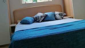 Een slaapkamer met een bed, een raam en een kledingkast.