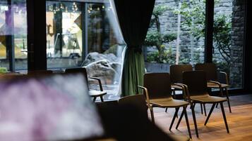 Ein Zimmer mit Holzboden, einem grünen Vorhang und mehreren Sitzgelegenheiten.