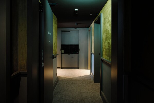 A narrow hallway with a carpeted floor leading to a room with a kitchenette. - BERGWELT GRINDELWALD | ALPINE DESIGN RESORT (Grindelwald)