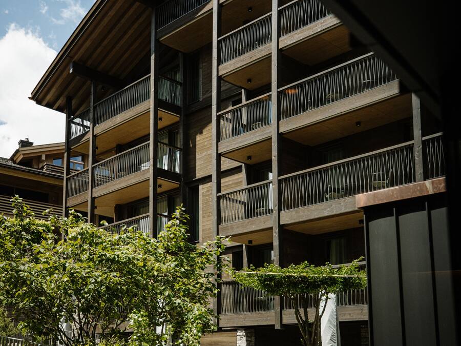 A multi-story building with balconies, a staircase, and a metal fence.