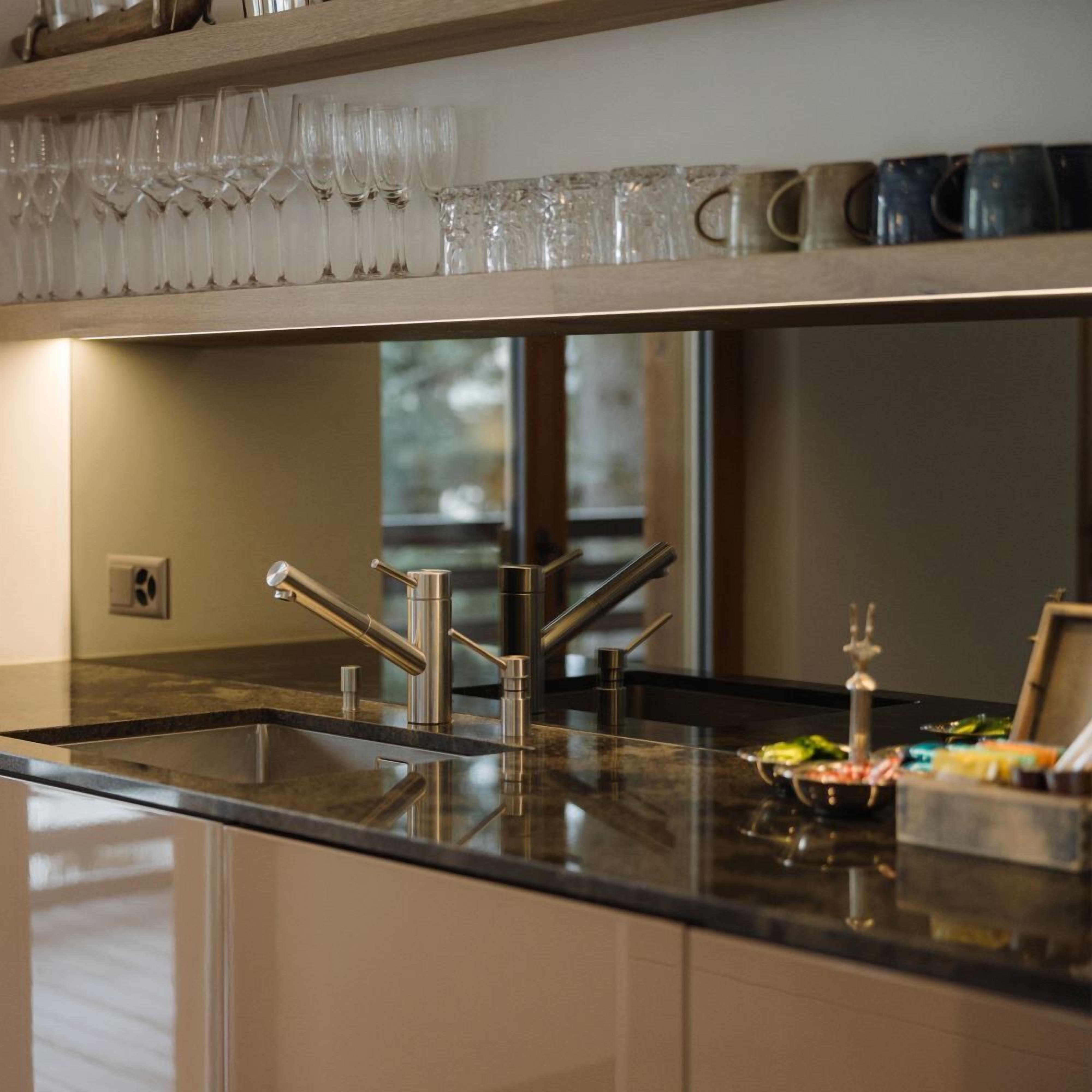 A kitchen with a stainless steel sink, a window, and a countertop with various items.