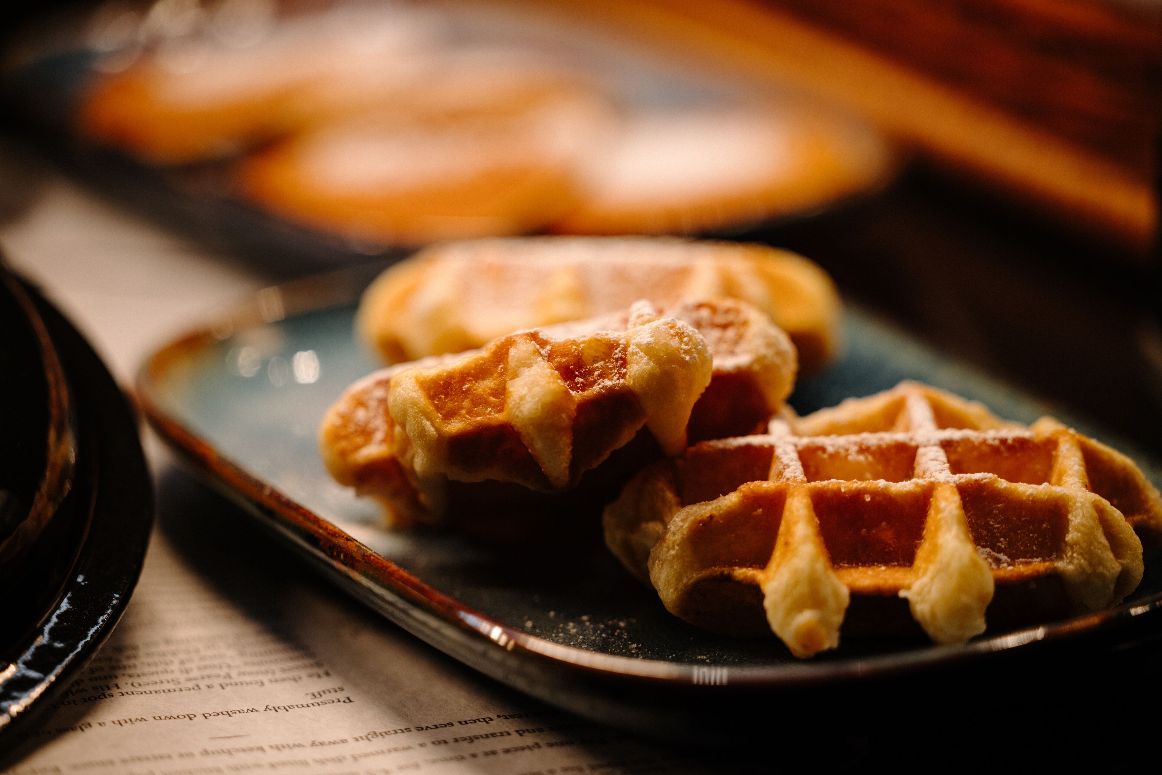 A close-up of waffles on a plate with a newspaper underneath.