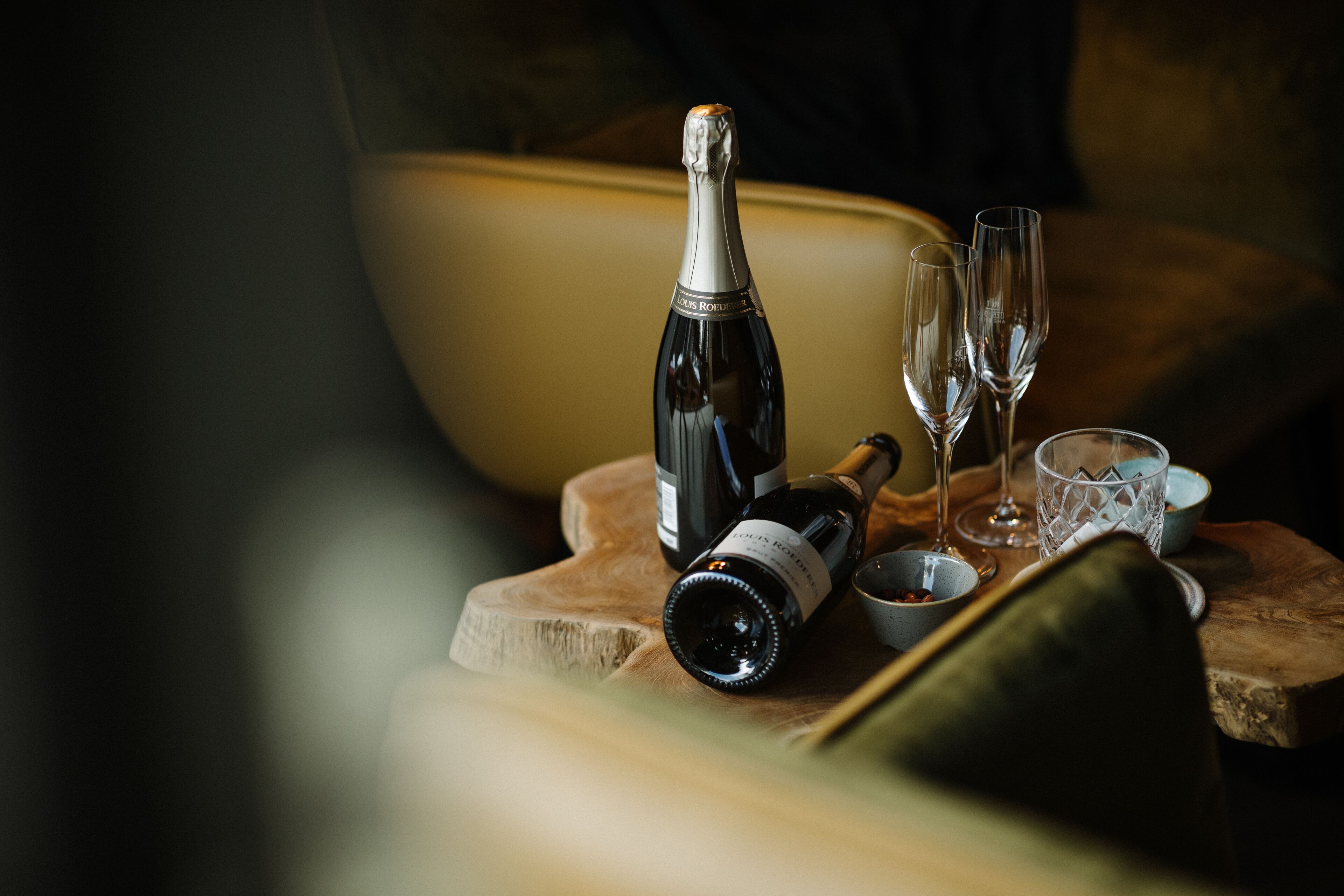 A bottle of wine, two glasses, and a bowl on a wooden surface.