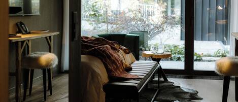 Un interior moderno con un sofá, una mesita redonda y una silla con reposabrazos mullidos.