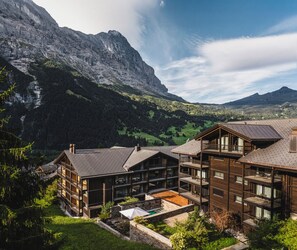 A mountain lodge with multiple wooden buildings, balconies, and a view of the surrounding mountains.