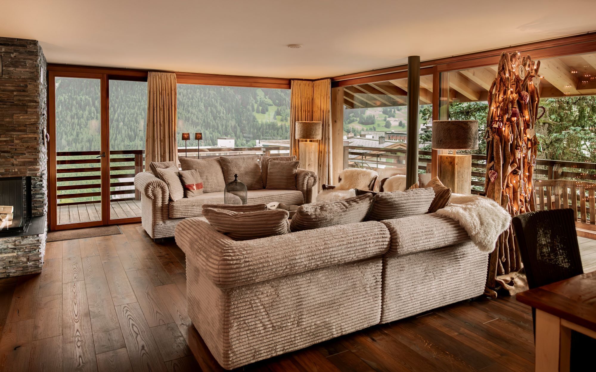 A cozy living room with a fireplace, a large sofa, and a view of the outdoors.