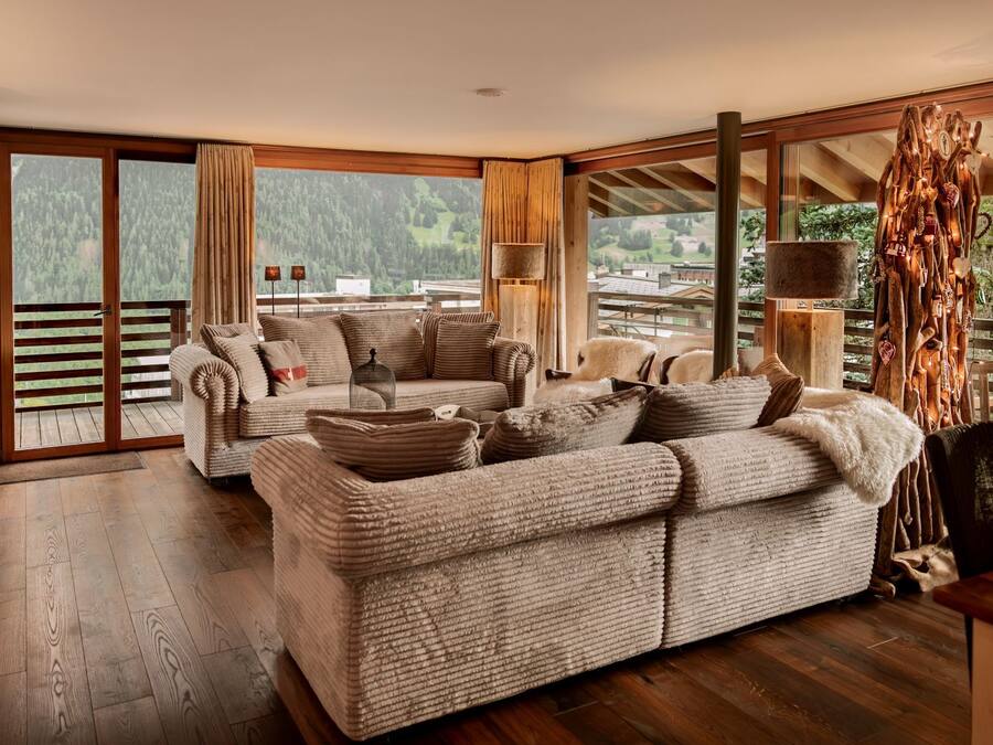 Una sala de estar acogedora con chimenea, un sofá grande y vistas al exterior.