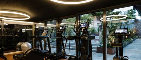 Un gimnasio con equipamiento de ejercicio, ventanas amplias y vistas al exterior.