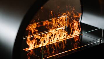 A close-up view of a wood-fired oven with visible flames inside.