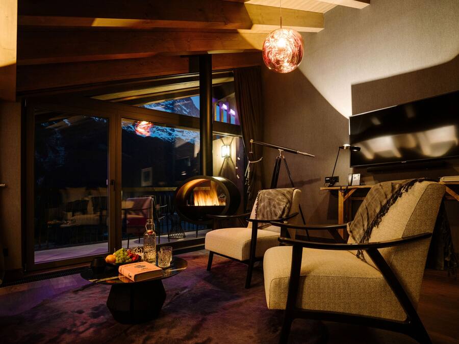 A modern living room with a fireplace, comfortable seating, a flat-screen TV, and a large window offering a view of the outdoors.