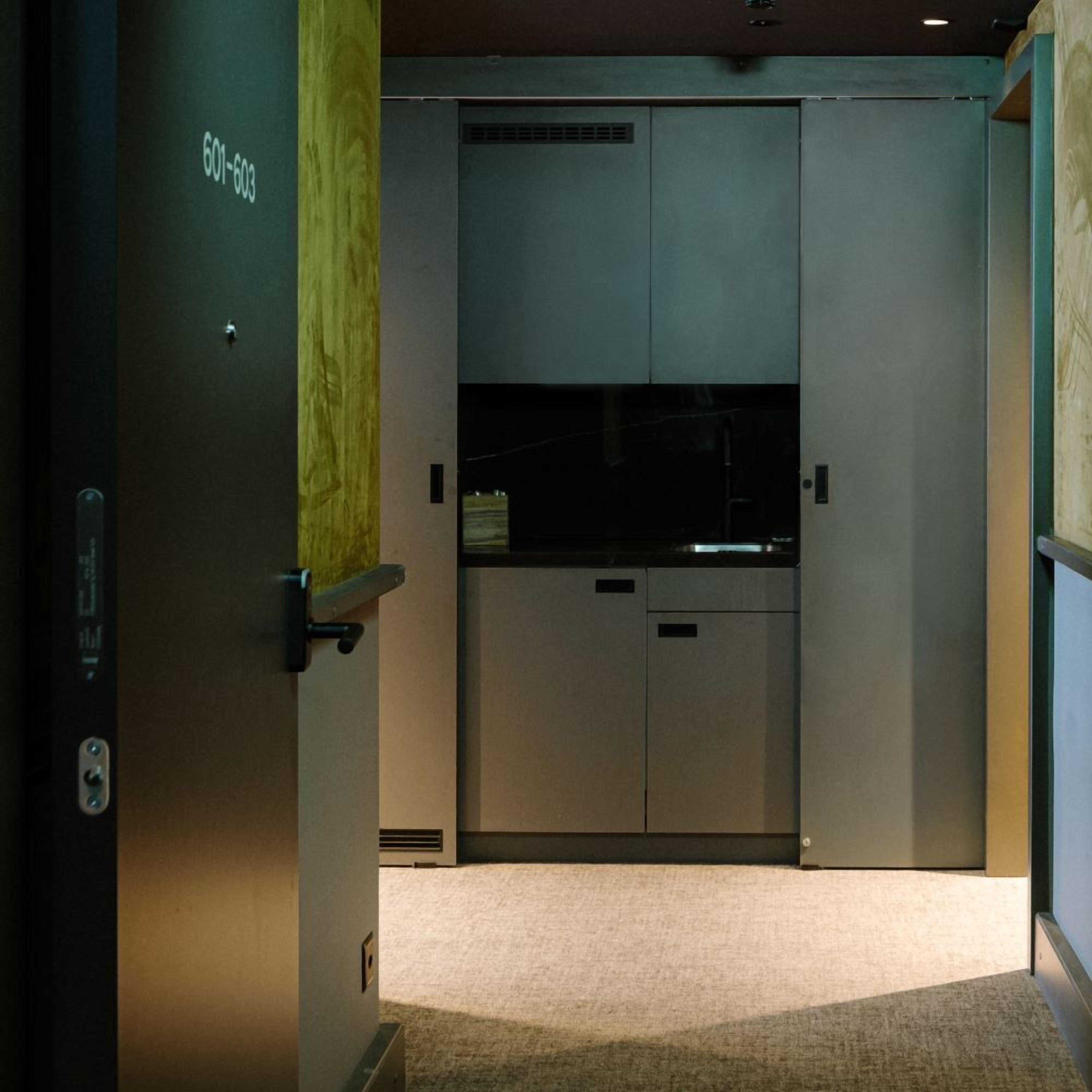 A hotel room with a sliding door, a small desk, and a carpeted floor.