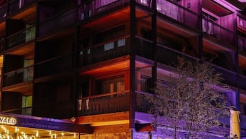 Um hotel de vários andares com varandas, fachada de pedra e uma placa com a inscrição 'BERGWELT GRINDELWALD ALPINE DESIGN RESORT'.
