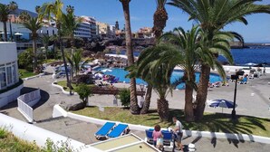A resort pool area with lounge chairs, palm trees, and a view of the ocean. - Fantastico 4 - with large private terrace, free parking, air conditioning, BBQ (Puerto de la Cruz)