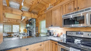 Una cocina con gabinetes de madera, encimeras de granito, un microondas de acero inoxidable y un horno empotrado.