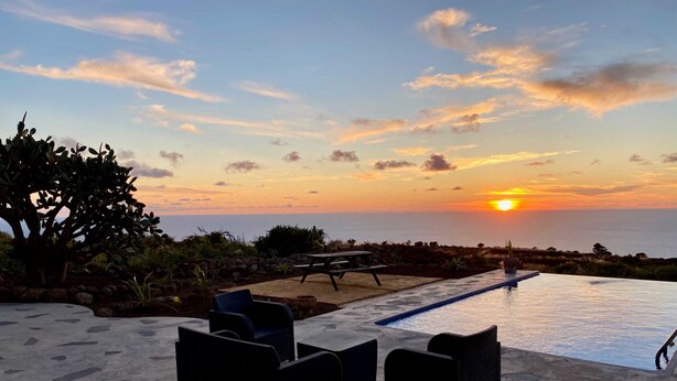 An outdoor pool area with lounge chairs and a view of the sunset over the ocean. - Casa Albillo, Spanien (Puntagorda)